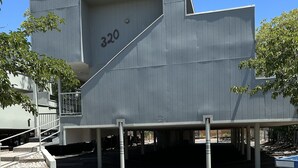 Um edifício moderno com telhado plano, o número '320' visível e um chão de concreto com cerca de metal.
