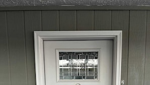 A white door with a number "2" above it, a small window with metal bars, and a doorbell.