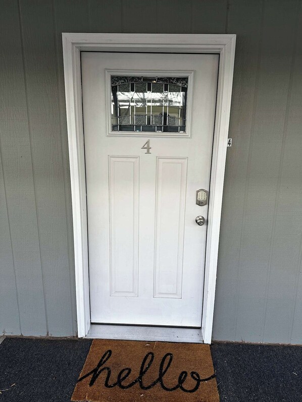 A white door with the number 4, a small window with bars, and a doormat with "hello" written on it.