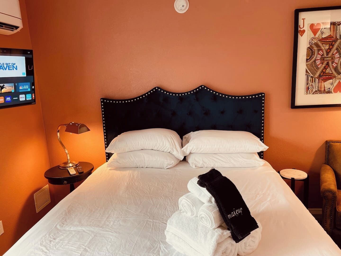 Une chambre d’hôtel avec un grand lit, un téléviseur fixé au mur, une petite table avec une lampe et une chaise.