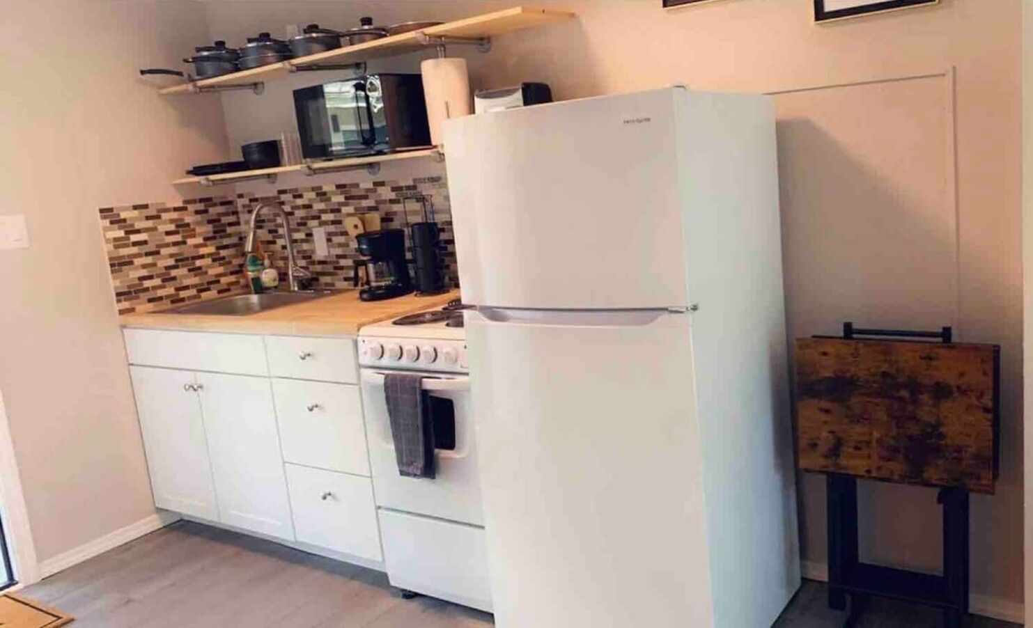 A compact kitchen with white cabinets, a stove, a microwave, and a refrigerator.