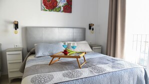 A neatly arranged bedroom with a bed, bedside tables, a wall-mounted painting, and a window with curtains. - Platero penthouse in the center of nerja (Nerja)