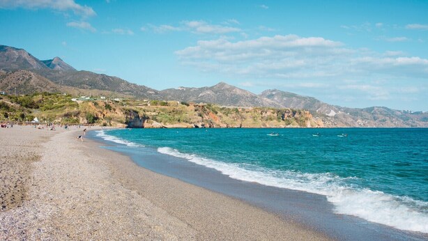 A pebble beach with clear turquoise waters and mountains in the background. - Platero studio in the center of nerja (Nerja)