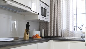 A modern kitchen with white cabinets, a microwave, a toaster, and a fruit plate. - Platero studio in the center of nerja (Nerja)