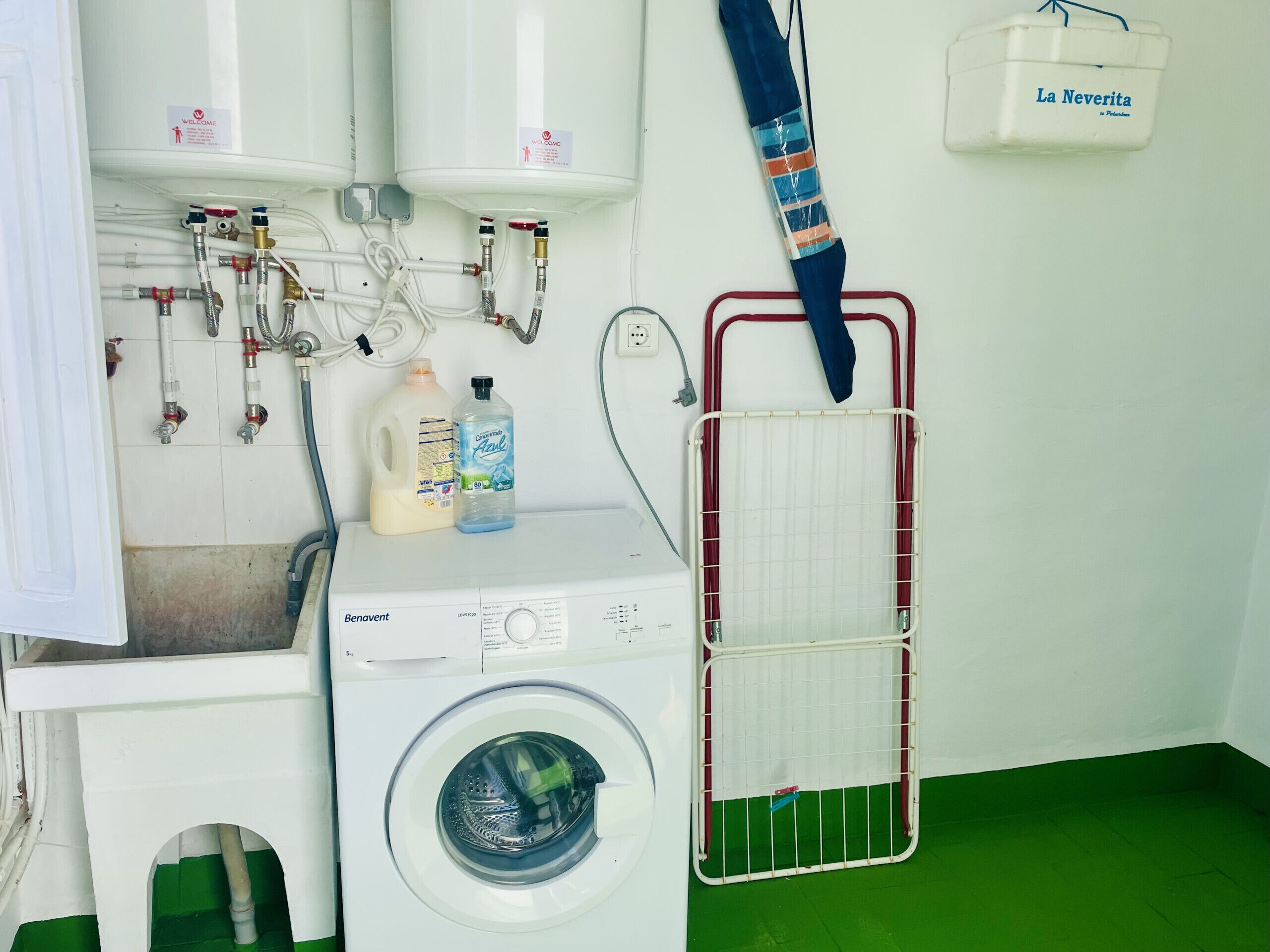 A laundry area with a washing machine, a drying rack, and a water heater.