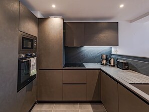 A modern kitchen with stainless steel appliances, a built-in oven, and a coffee maker.