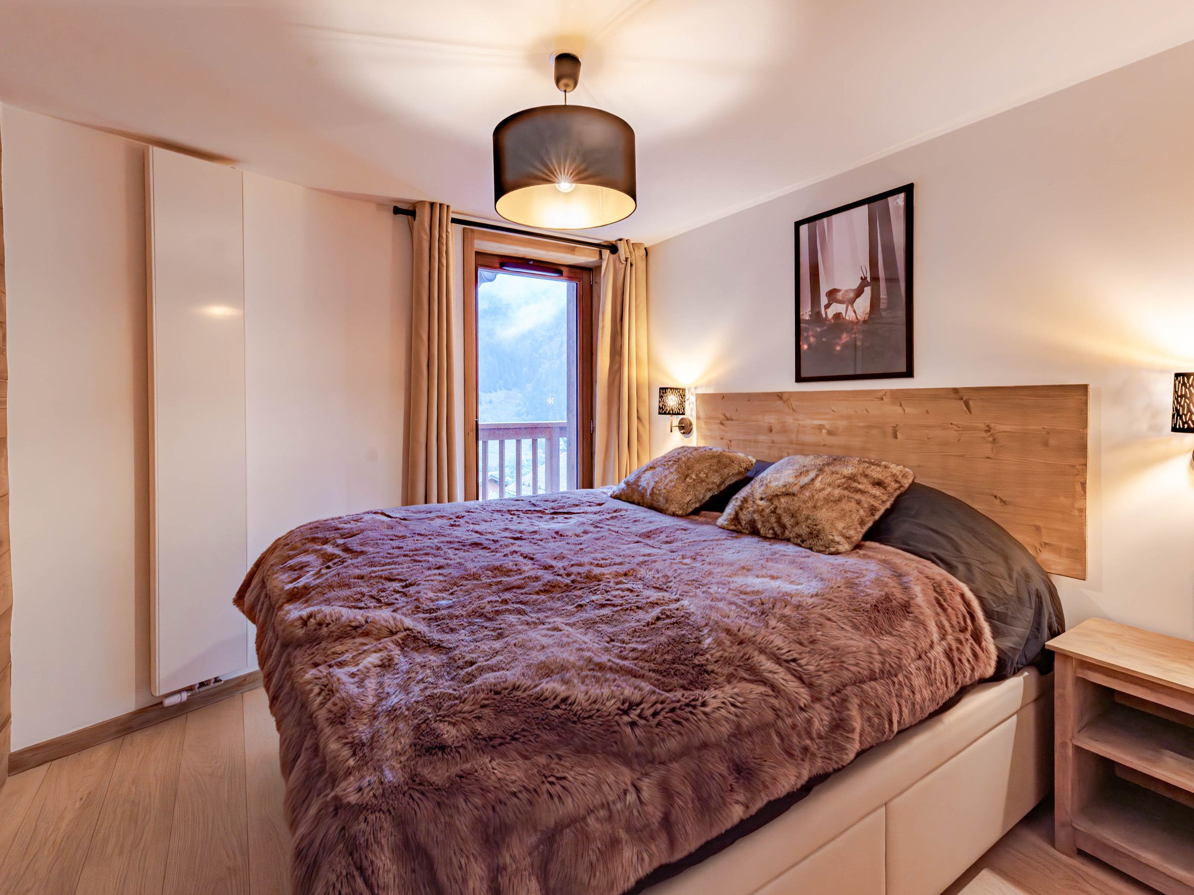 Quarto com cama grande, cabeceira de madeira e janela com cortinas.