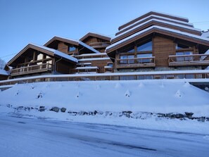 Ein mehrstöckiges Holzhaus mit Balkonen und einer verschneiten Landschaft.