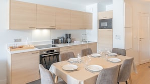 Une cuisine moderne avec des meubles en bois, une table à manger pour quatre personnes et un four encastré.