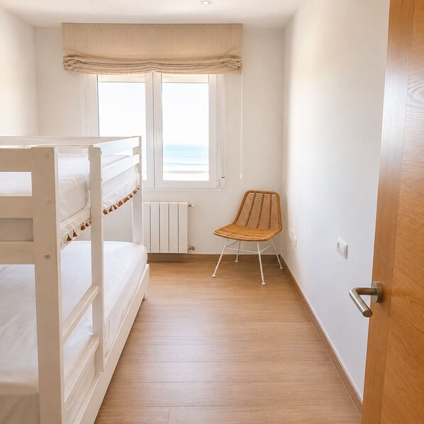 A room with bunk beds, a chair, a window with a view, and a radiator.