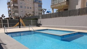 Une piscine extérieure rectangulaire, dotée d’un escalier en métal et d’une clôture de sécurité.