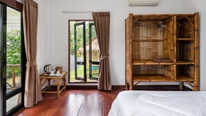 A room with a bed, a wooden wardrobe, a table with a kettle and cups, and a window with curtains. - Tropical Heavens Garden Samui (Koh Samui)