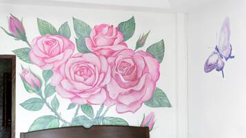 A bedroom with a bed, a wall mural of pink roses, and a butterfly.