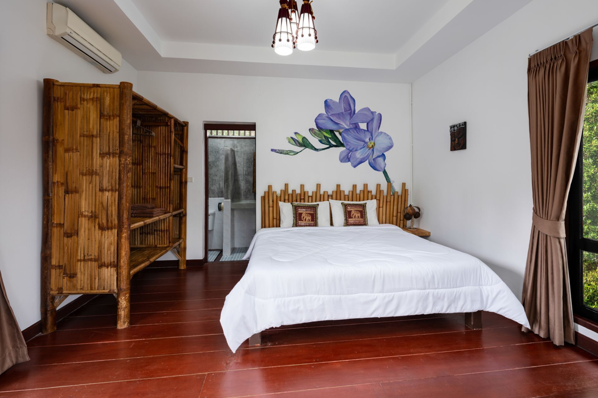A bedroom with a large bed, a wooden wardrobe, and a bathroom visible through an open door.