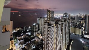 A high-rise building complex with multiple floors, large windows, and a view of the cityscape at night. - Budget Stay with Bay & City Lights View (Manila)