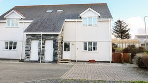 Une maison à deux étages avec une façade en pierre, un toit en tuiles et une entrée principale dotée d’une double porte.