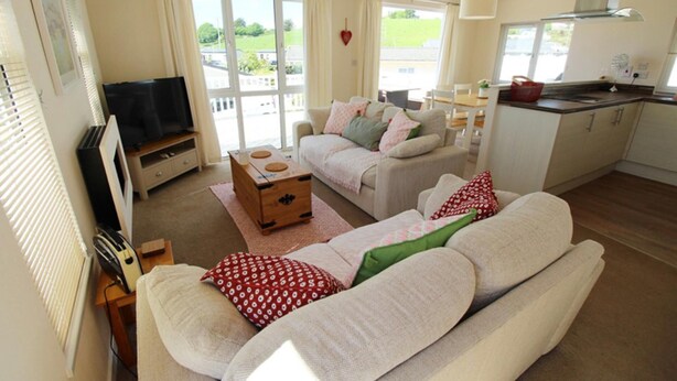 A cozy living room with a sofa, a television, and a small wooden table. - Charming 3-bed Chalet in Abersoch (Pwllheli)
