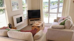 A living room with a sofa, a television, and a wooden box. - Charming 3-bed Chalet in Abersoch (Pwllheli)