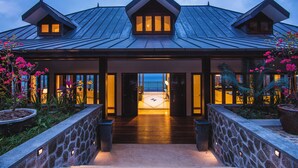 A modern building with a stone facade, large windows, and a well-lit entrance. - Villa Salazie (Mahé Island)