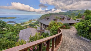 A coastal resort with a stone pathway leading to a building with a tiled roof, surrounded by lush greenery and overlooking the sea. - Villa Salazie (Mahé Island)