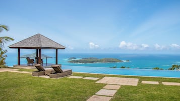 A gazebo with outdoor seating, a swimming pool, and a view of the ocean and islands.