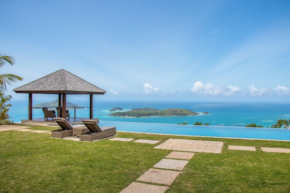 Un pabellón con asientos al aire libre, una piscina y vistas al océano y a las islas.