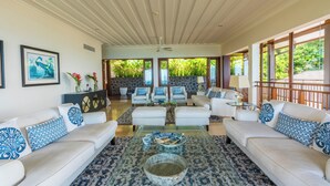 A spacious living room with a high ceiling, a glass coffee table, and a seating area with sofas and armchairs. - Villa Salazie (Mahé Island)