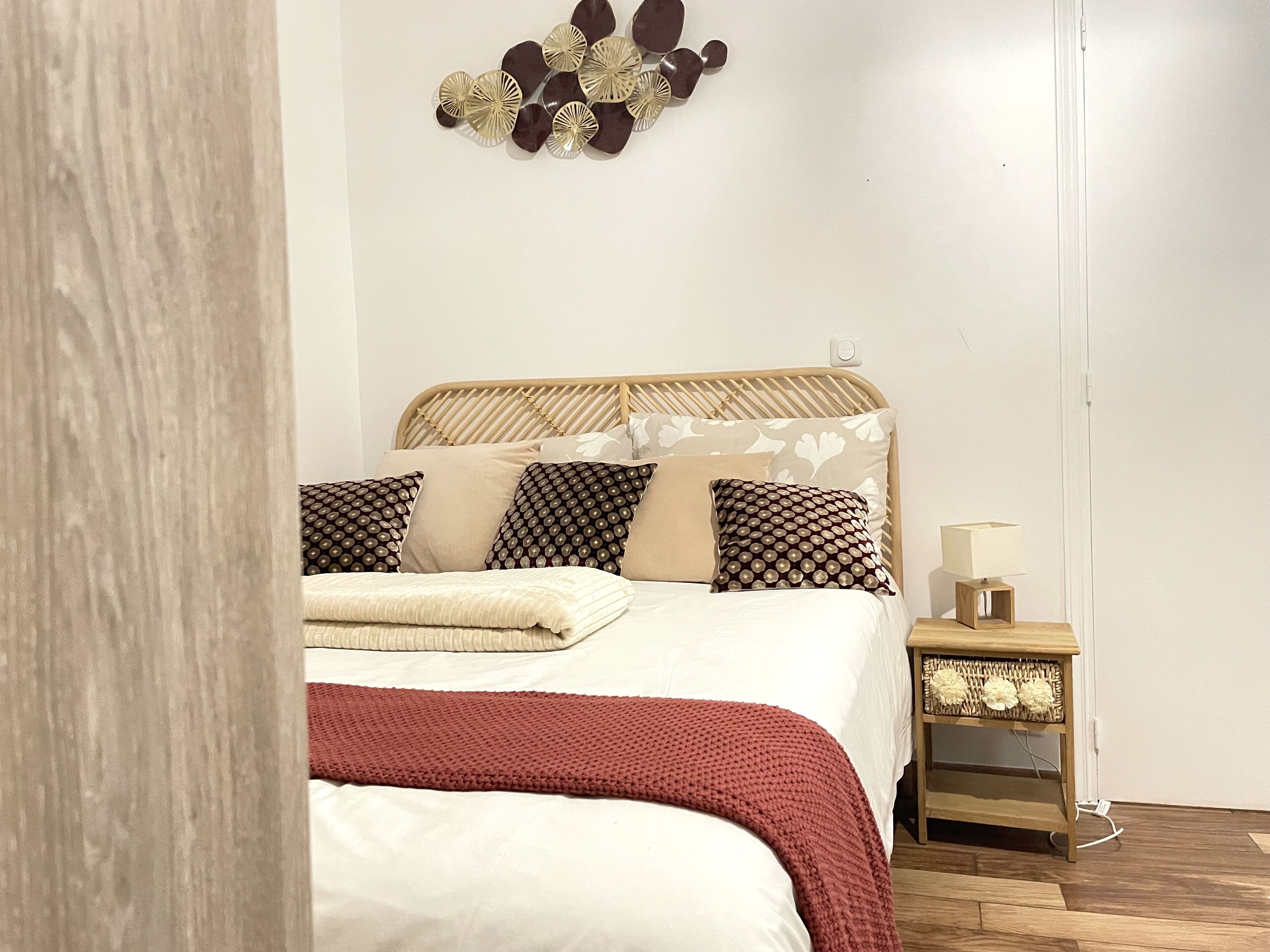 A bedroom with a bed, pillows, a bedside table, and a wall decoration.