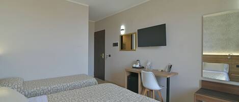Ein Hotelzimmer mit zwei Betten, einem Schreibtisch mit Stuhl, einem Spiegel und einem kleinen Tisch.