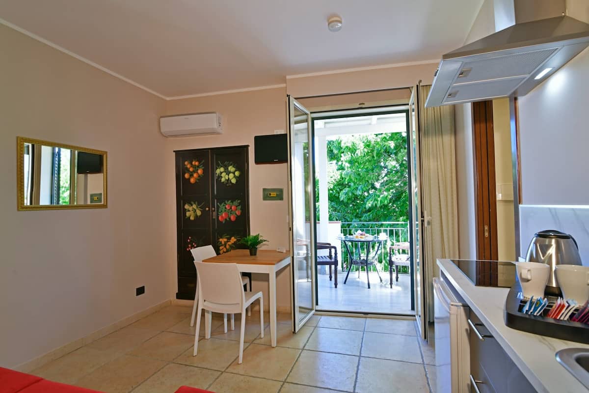 Una cocina moderna con comedor, puerta de vidrio corredera que da a un patio exterior y un equipo de aire acondicionado visible.