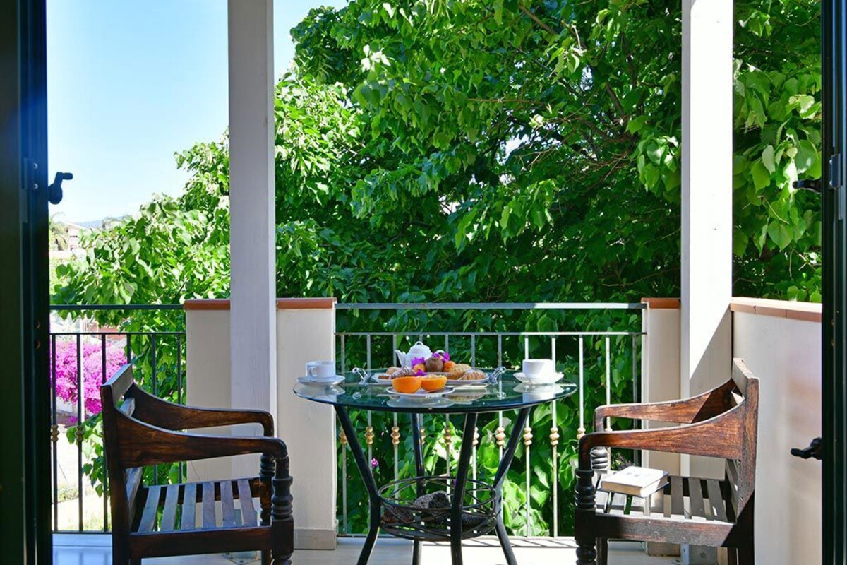 Een balkon met een ronde tafel, twee houten stoelen en een klein mandje.