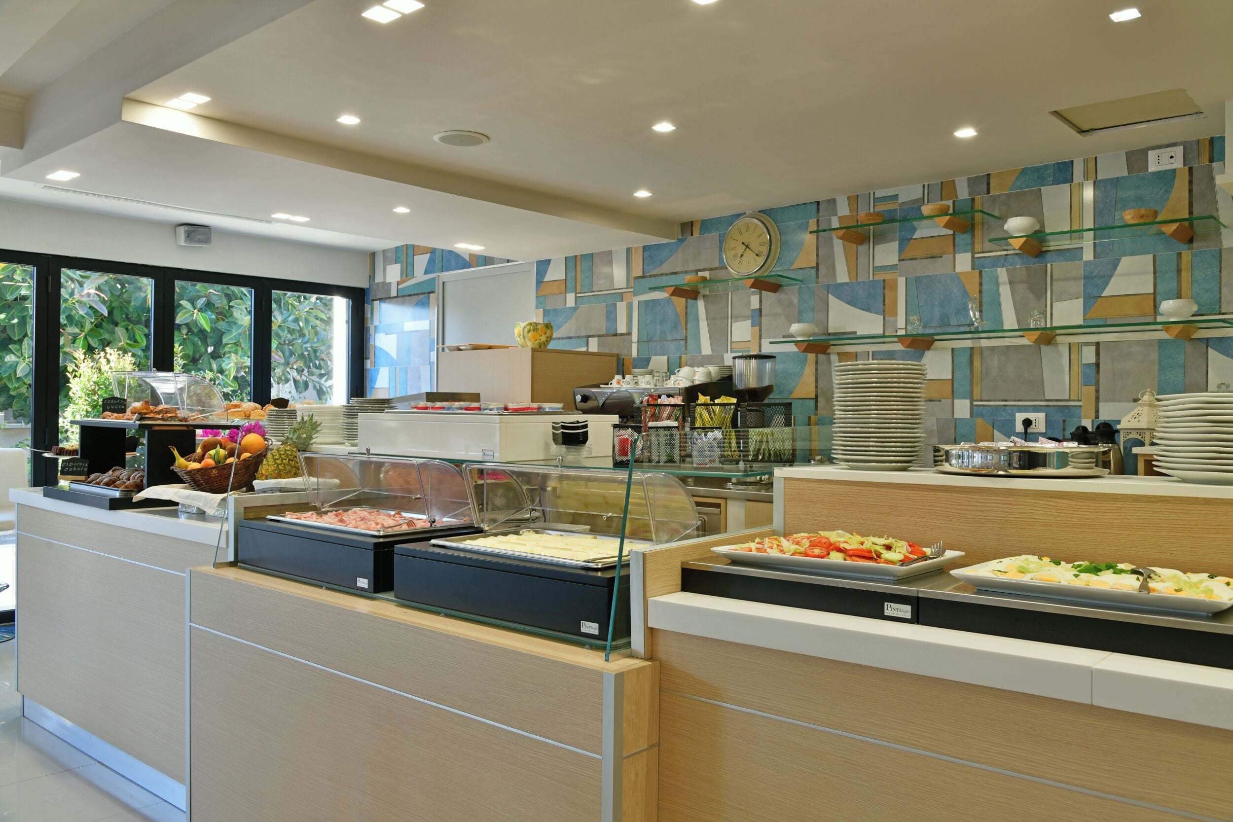 A buffet area with various food options, a clock on the wall, and a modern interior design.
