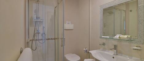 A bathroom with a glass shower enclosure, a toilet, a sink with a mirror, and a towel rack.