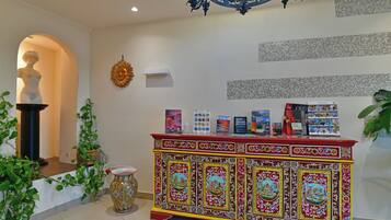 A reception area with a decorative red and yellow cabinet, a statue, and a wall with text.