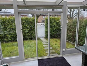 A modern room with a sliding glass door leading to a garden. - 3Br House, Sleeps 7 With Balcony-garden-bbq-freep (Malmö)