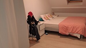 Makuuhuone, jossa on sänky, tuoli, ikkuna ja ovi.