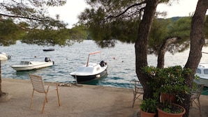 Zona frente al lago con barcos amarrados, un paseo marítimo de hormigón y plantas en macetas.