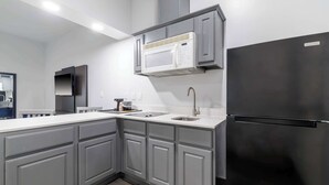 Una cucina moderna con mobili grigi, un frigorifero nero, un forno a microonde e un lavello.