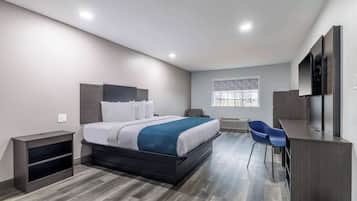 A modern hotel room with a large bed, a desk, a chair, and a window.
