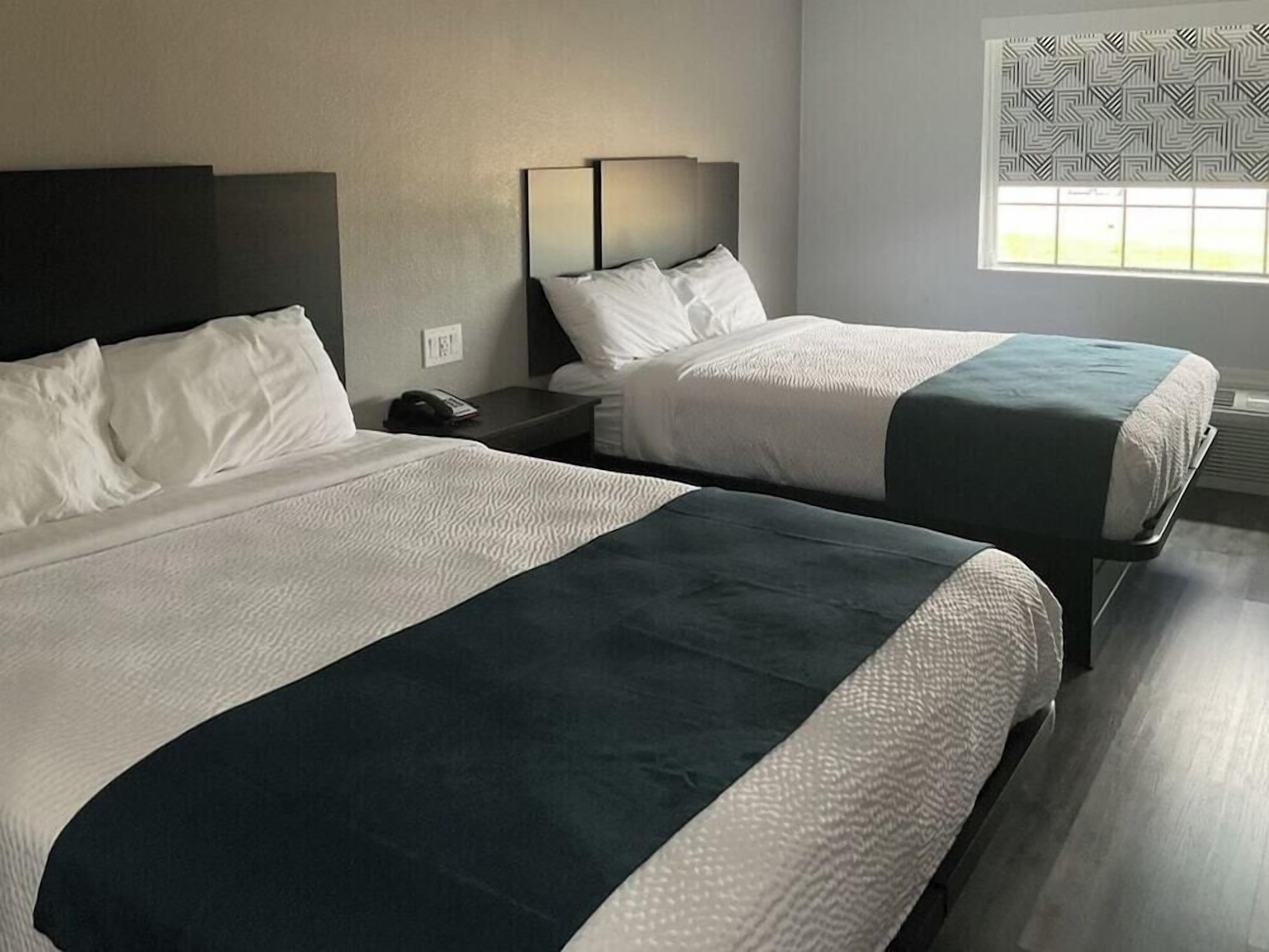 Two single beds with white bedding and dark headboards in a hotel room.