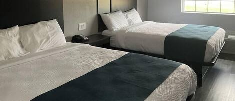 Two single beds with white bedding and dark headboards in a hotel room.
