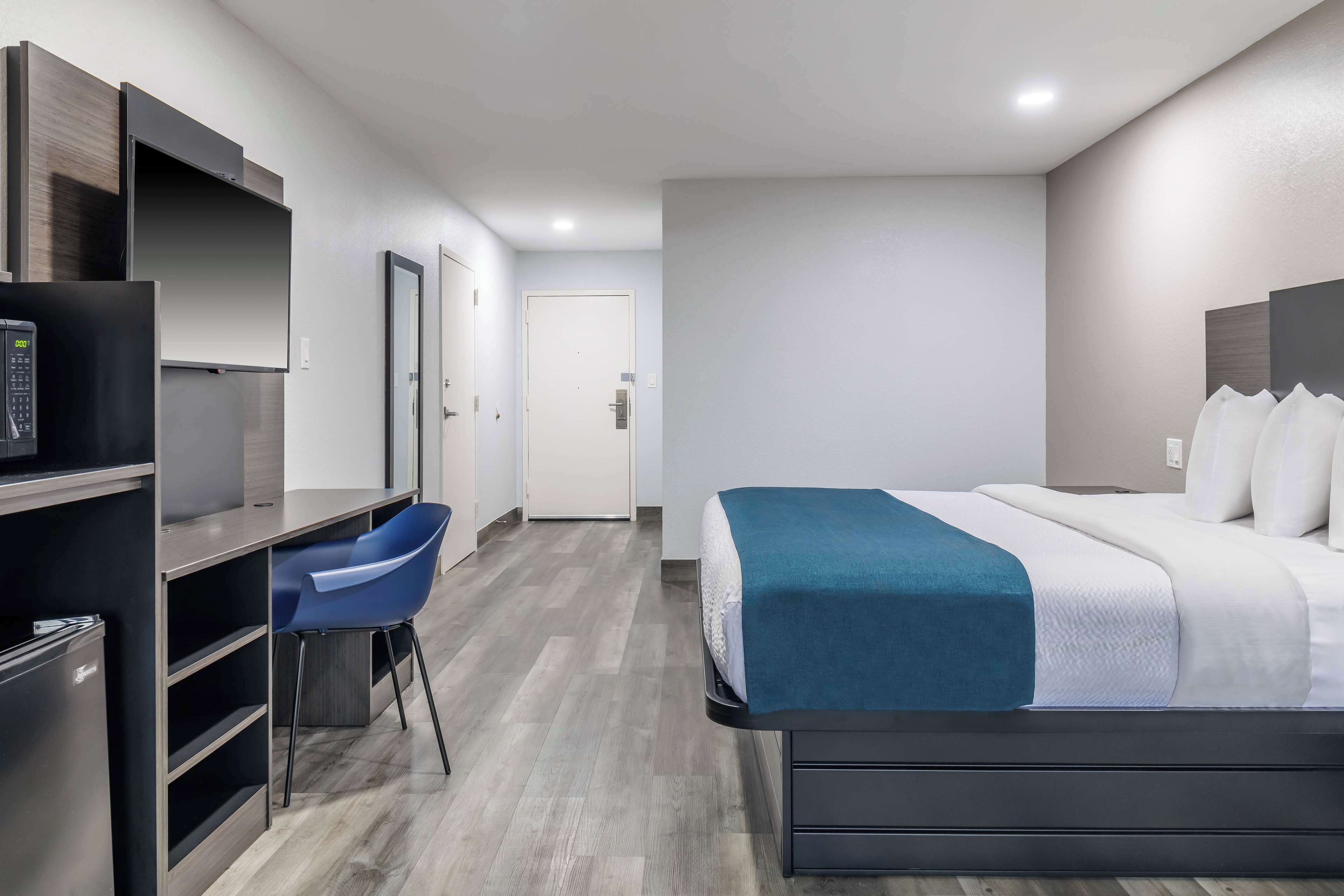 A modern hotel room with a bed, a desk, and a chair.