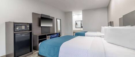 A hotel room with a bed, a small refrigerator, a desk with a chair, and a television.