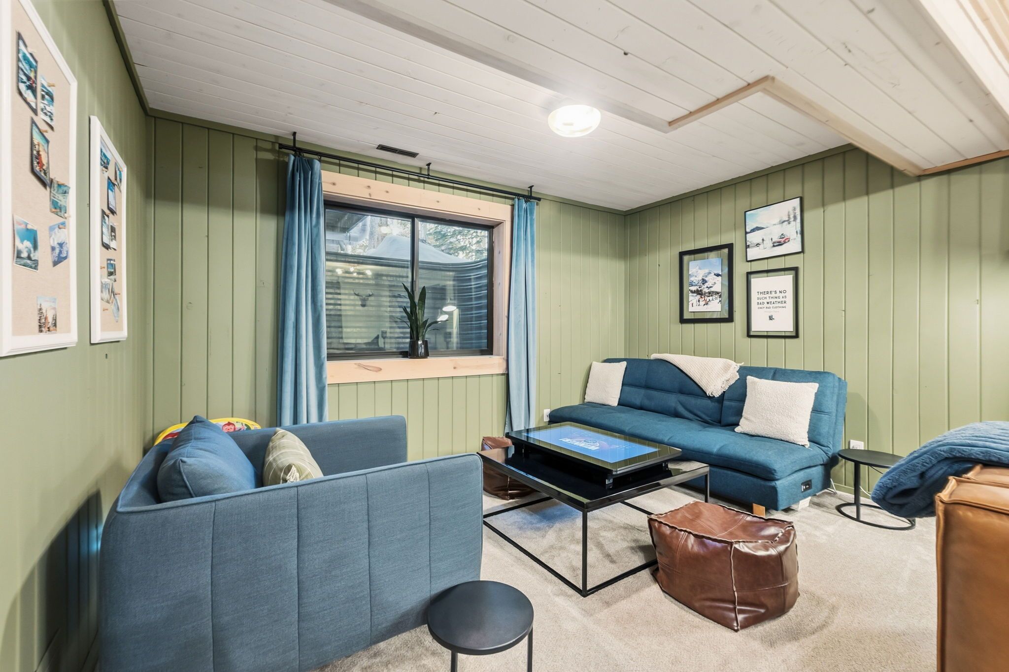 A cozy room with a blue sofa, a coffee table, and a window with curtains.
