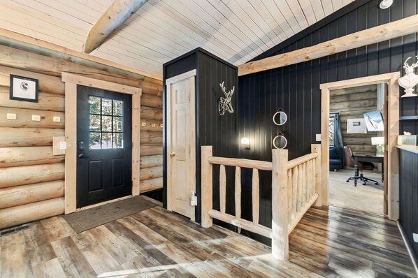 A log cabin interior with a wooden staircase, a black door, and a framed picture on the wall. - SkiHytte🎿 Scandinavian Cabin 🪵 Forest Views 🌲 Pets OK 🐶 $0 Cleaning Fee (Breckenridge)