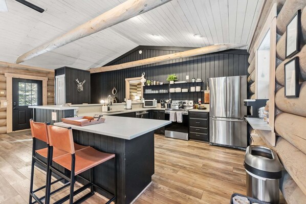 Una cocina moderna con una isla central, electrodomésticos de acero inoxidable y detalles de madera.