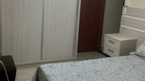 Ein Schlafzimmer mit Bett, Schrank, Nachttisch und Deckenventilator.