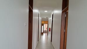 Un long couloir étroit aux murs blancs et aux encadrements de porte en bois.