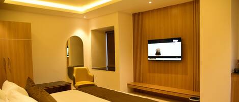 Una habitación de hotel moderna con una cama grande, un televisor montado en la pared y un armario de madera.
