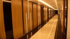 A long, well-lit hallway with wooden doors and a shiny floor. - Hotel Grand Serene Mysore (Mysore)